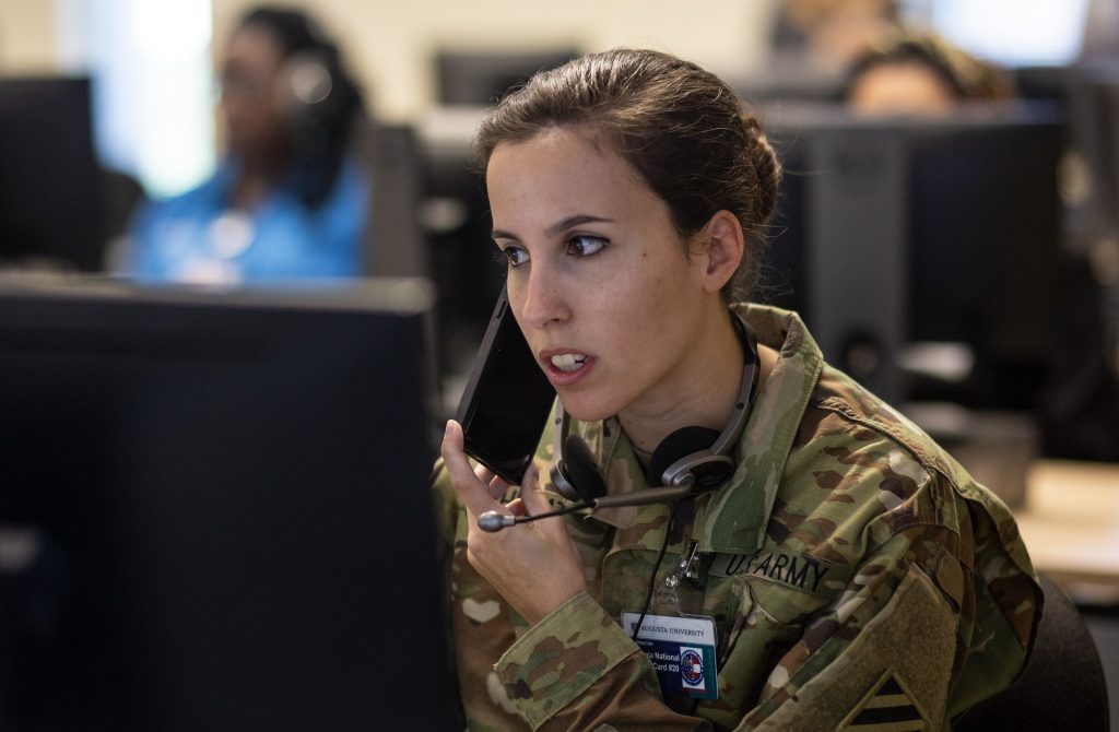 In this Tuesday, April 28, 2020, photo, Georgia National Guard 2nd Lt. Adreana Chebat works alongside staff at Augusta University pre-screening people by phone for possible coronavirus testing at Augusta University Health Sciences Building in Augusta, Ga. Acknowledging his own “frustration” with the lack of testing in Georgia, Kemp rolled out plans on April 20 to use National Guard troops as well as clinicians and other staff from Augusta University's medical schools to dramatically ramp up testing. (AP Photo/Ron Harris)