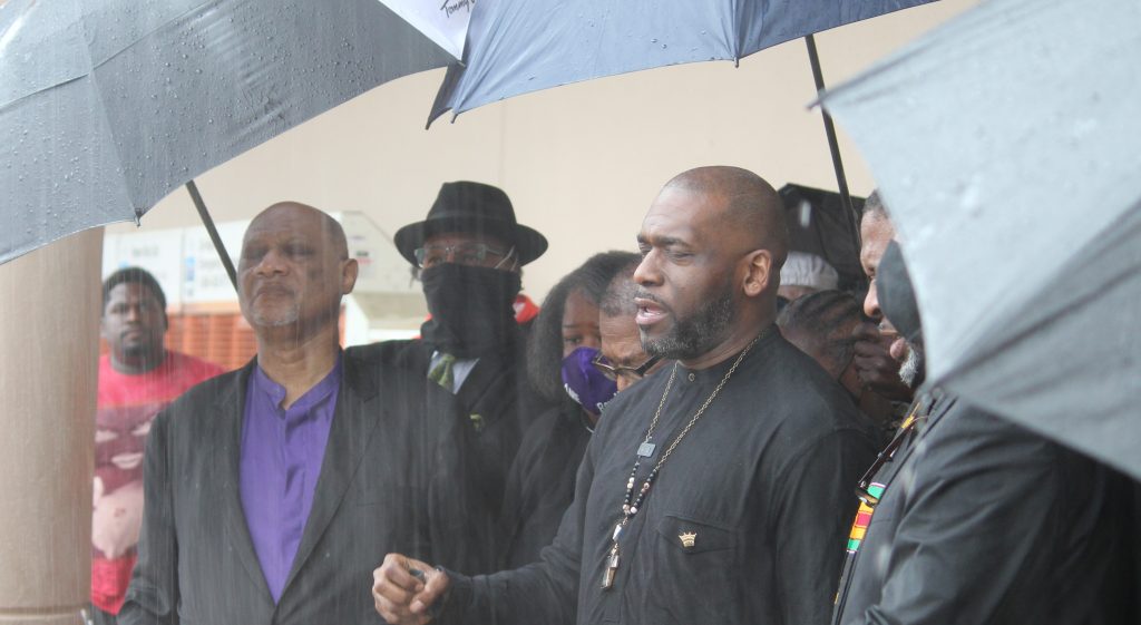 Surrounded by other faith leaders, Atlanta Pastor Jamal Harrison Bryant prays outside Home Depot. The group is currently waging a boycott against the company. (Emil Moffatt/WABE)