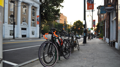 Several black bikes are locked to a bike rack along a city street in downtown Atlanta.