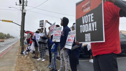 Activists hold signs urging people to vote on the side of a road in Decatur.