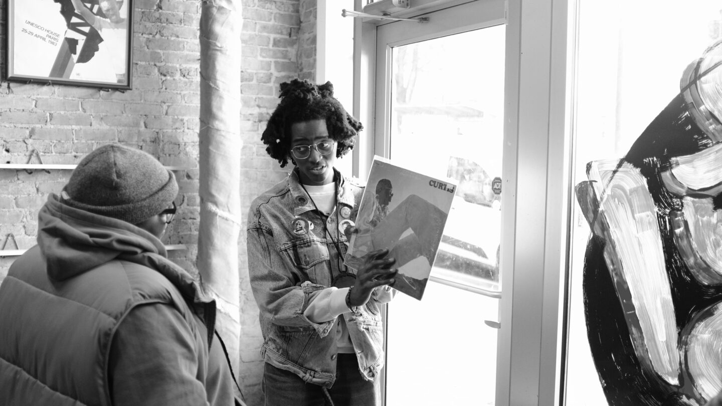 Black & White photo of man holding up record in store