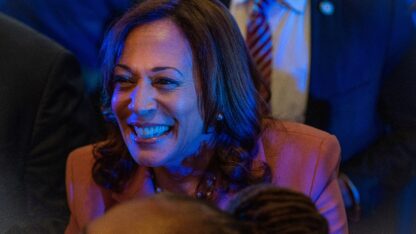 Kamala Harris smiles as a blue light illuminates her at a campaign stop in May 2023.