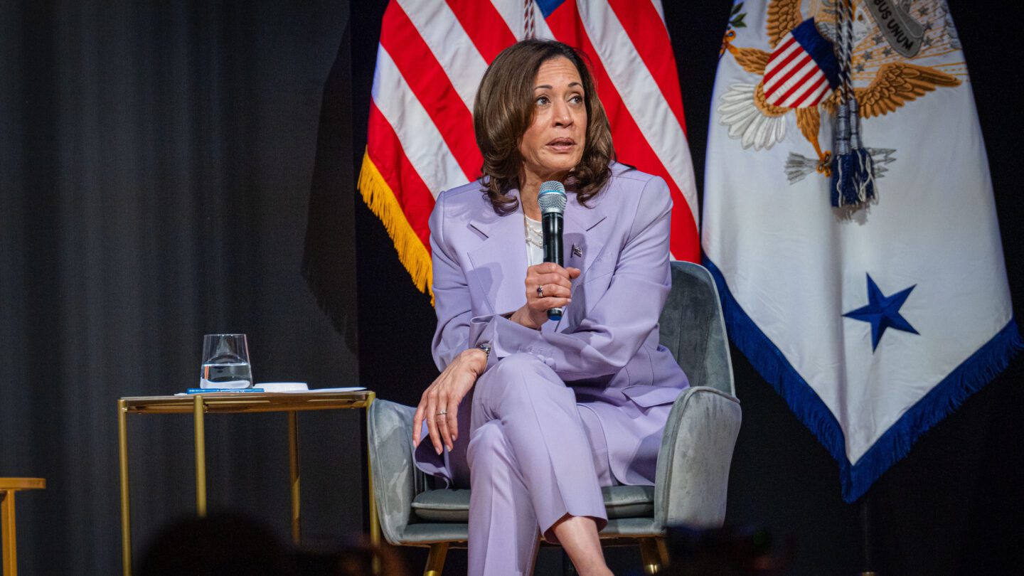 Kamala Harris sits on stage at the Rocket Foundation summit, microphone in hand.