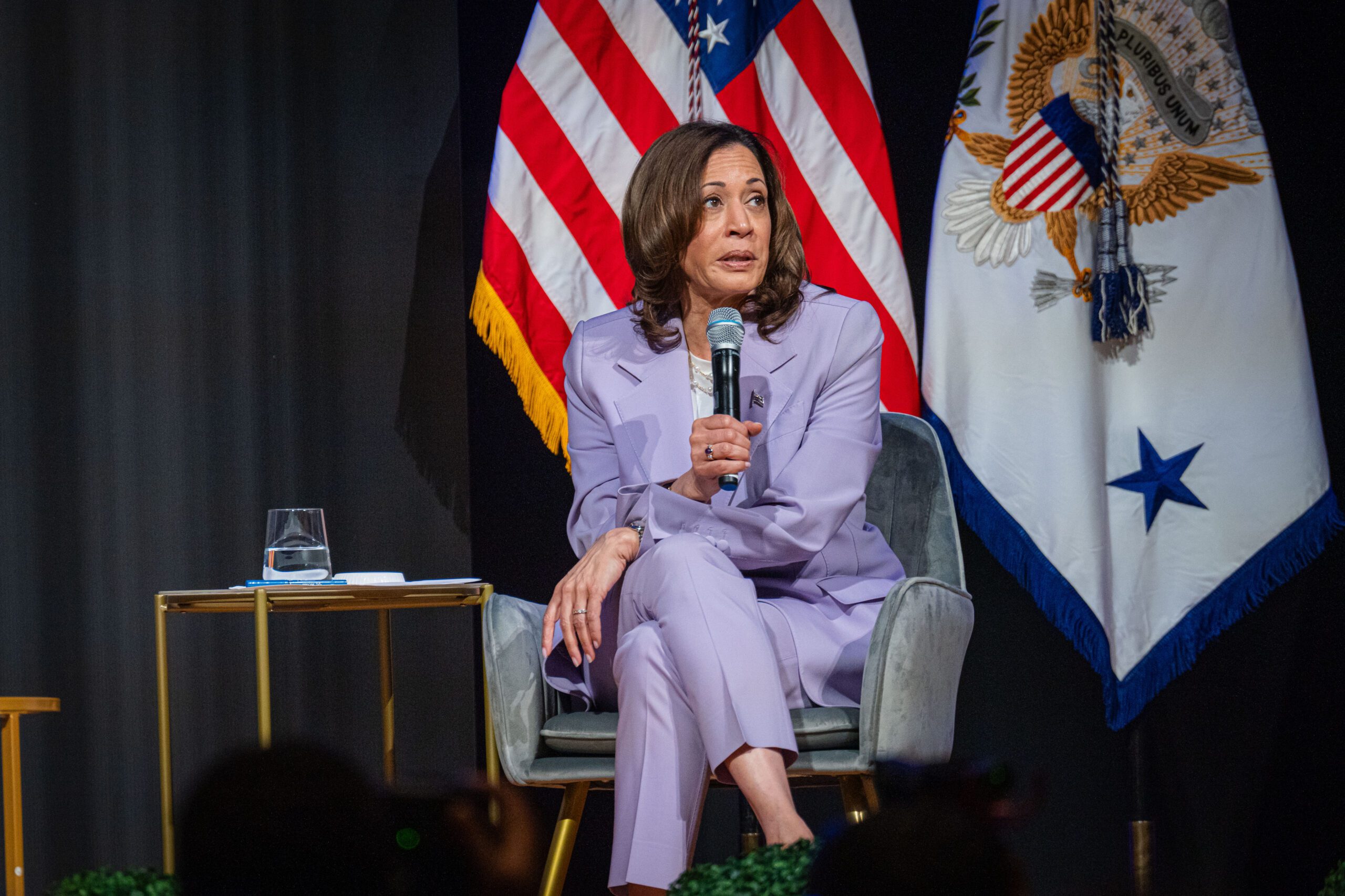 Kamala Harris sits on stage at the Rocket Foundation summit, microphone in hand.