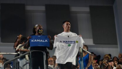 Attendees at Kamala Harris's campaign rally in Atlanta on July 30, 2024, hold up a sign and t-shirt that spell out the presumptive nominee's name.