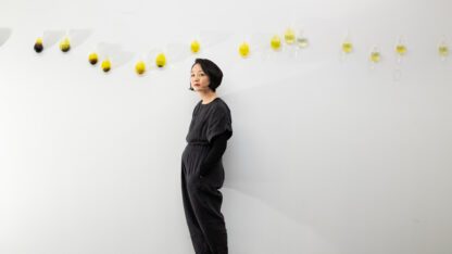 Gyun Hur stands beside her hand-blown glass vessels of local river water in her studio.