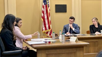 U.S. Sen. Jon Ossoff listens to testimony from physicians at a Senate subcommittee field hearing in Decatur. An American flag stands in the background of the hearing room.