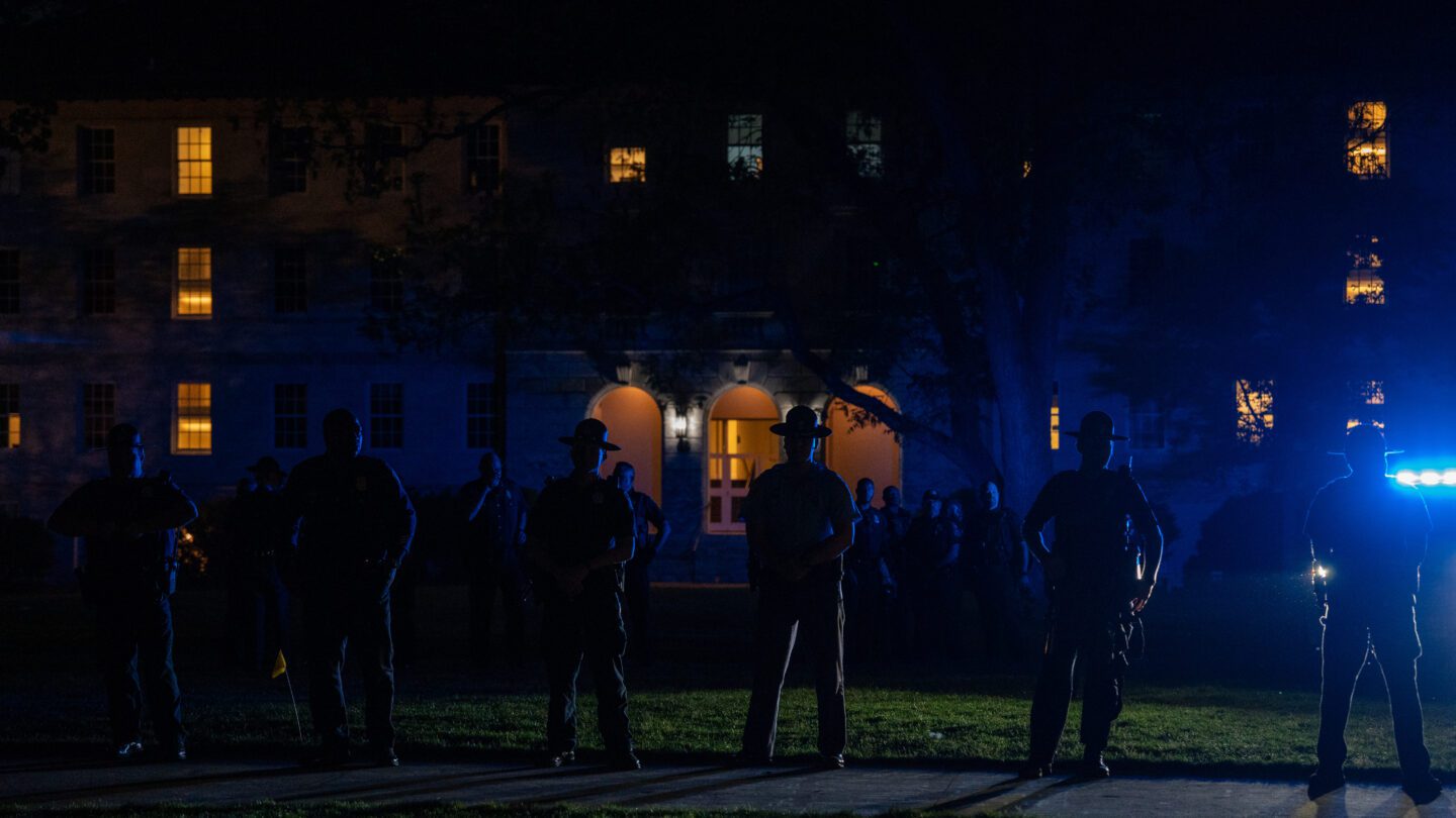 The Georgia State Patrol form a line on the quad on the campus of Emory University during a night of Pro-Palestinian protests on Thursday, April 25, 2024. The blue light of a police car is visible in the background.