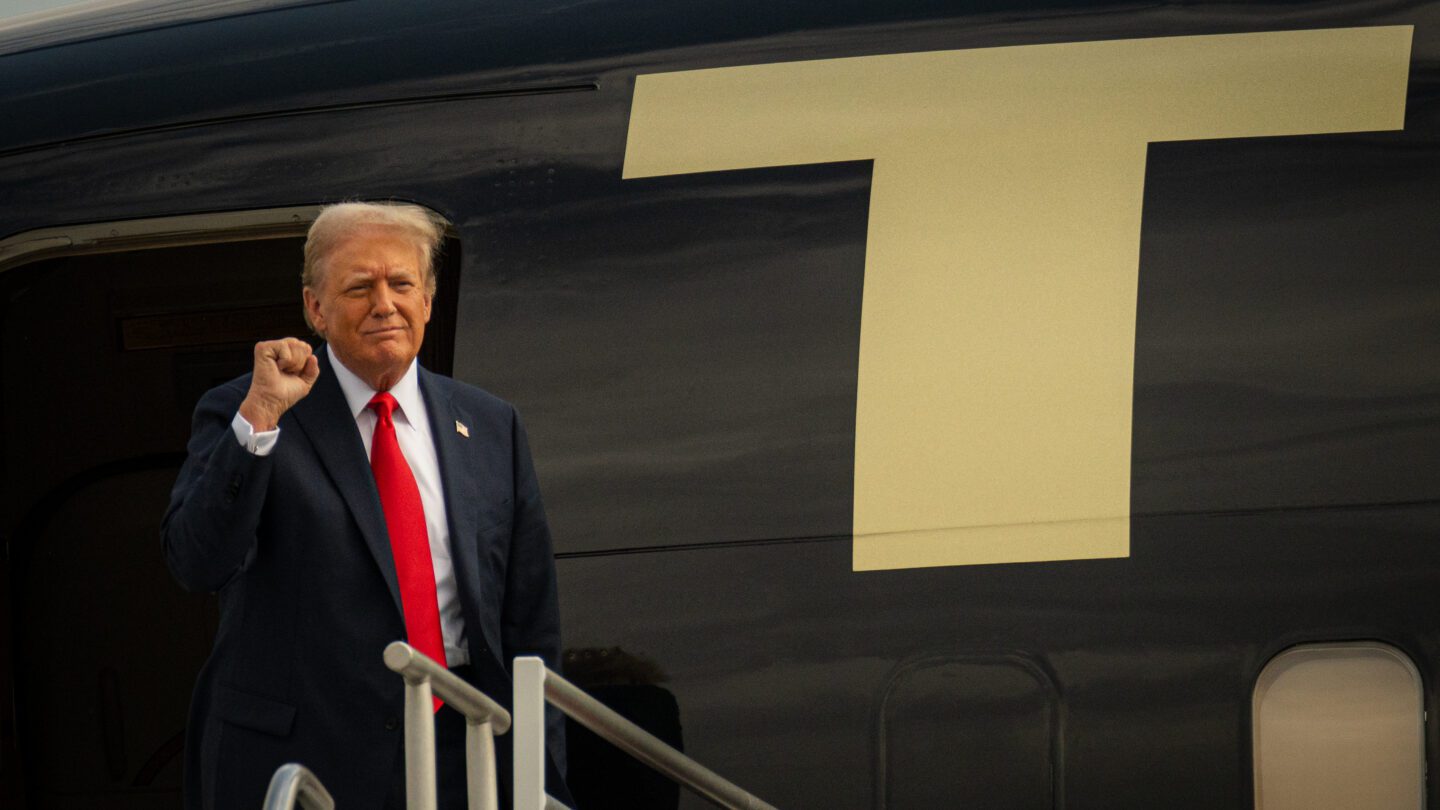 Former President Donald Trump raises a fist in greeting as he exits from his private jet at the Atlanta airport.