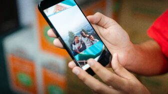 Adam Davis holds his phone, showing a photo of himself, his dad and his older brother posing on top of a mountain in Ethiopia.