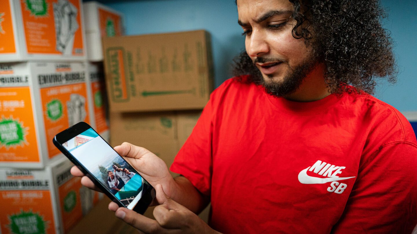 Adam Davis holds a phone to show a picture of him, his dad and his older brother in Ethiopia.