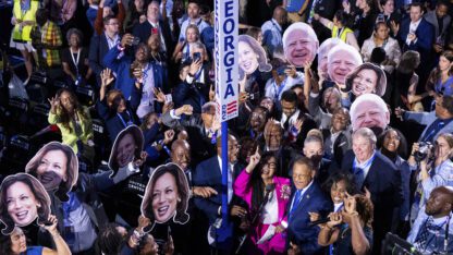 A crowd of Georgia delegates hold up cardboard cutouts of Kamala Harris and Tim Walz at the Democratic National Convention.