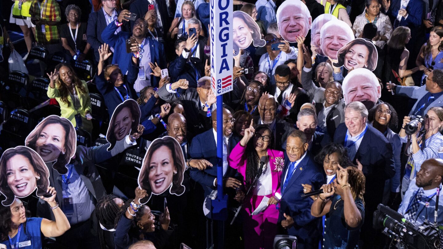 A crowd of Georgia delegates hold up cardboard cutouts of Kamala Harris and Tim Walz at the Democratic National Convention.