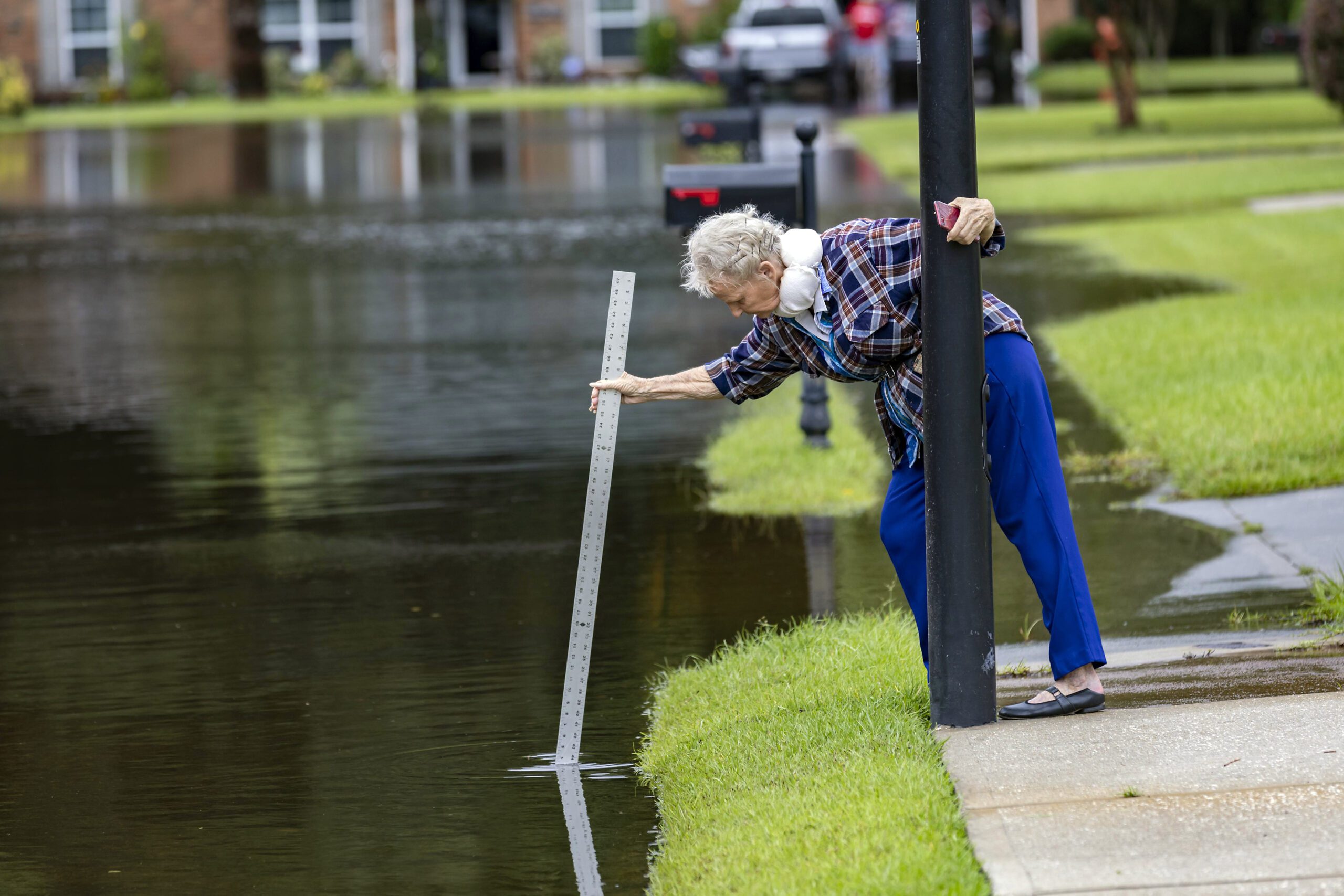 A resident measures the depth of the flooded street with storm water from Tropical Storm Debby.