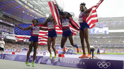 Sha'carri Richardson,Gabrielle Thomas, Twanisha Terry, and Melissa Jefferson, of the United States jump in unison, each holding American flags behind them.