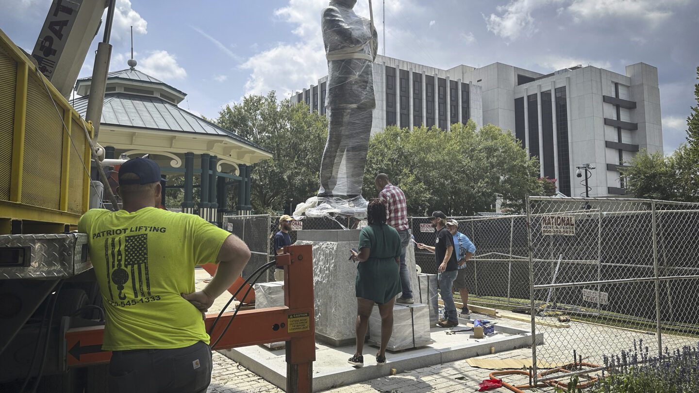 A large lift installs a statue of late civil rights leader and politician Congressman John Lewis.