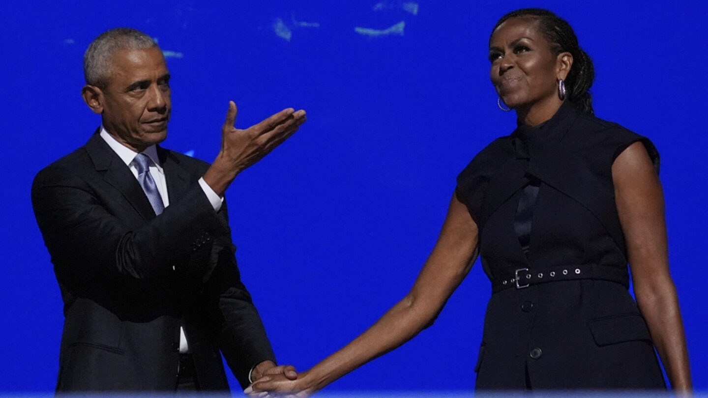 Barack Obama holds Michelle Obama's hand at the 2024 Democratic National Convention in Chicago after her speech.