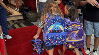 Hope-Hill students with colorful backpacks walk the red carpet on the first day of school.