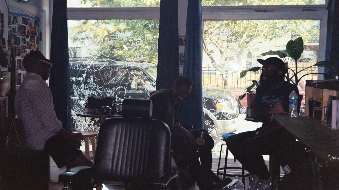 Ernest Hood (left), Devron Barrett (middle), and Javon Lee (right) sit in front of the window at a barbershop