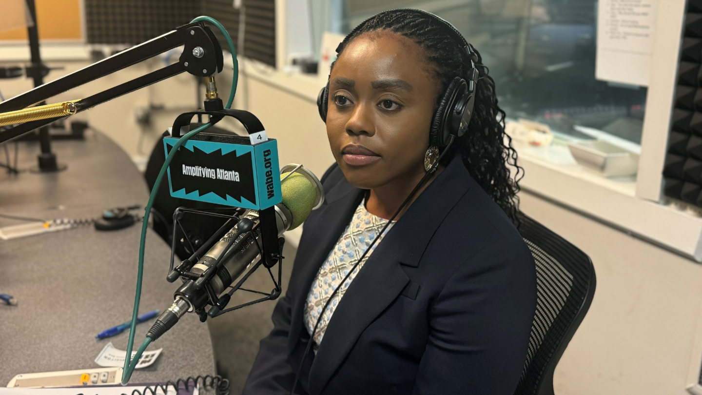 Esosa Osa sits in front of a podcast microphone at the WABE studio.