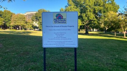 A sign saying This is City Schools of Decatur Property on a green field.