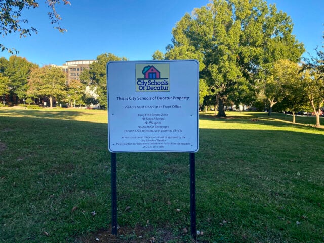 A sign saying This is City Schools of Decatur Property on a green field.