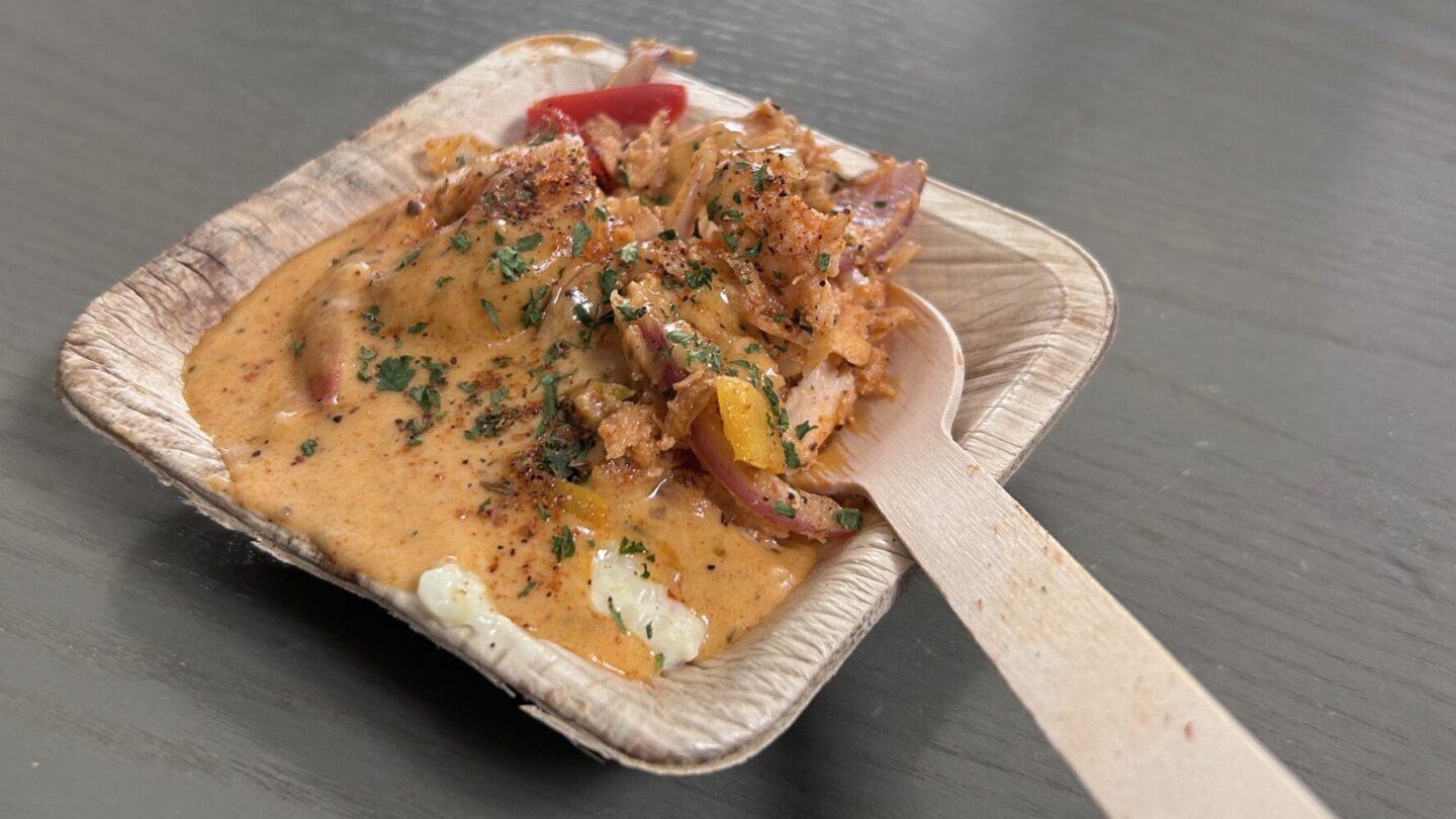 Plate of grits topped with peppers and grilled shrimp in a golden Cajun cream sauce.