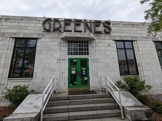 The front of he Greene's Fine Foods store, which has a green door with large lettering spelling out GREENES above it.