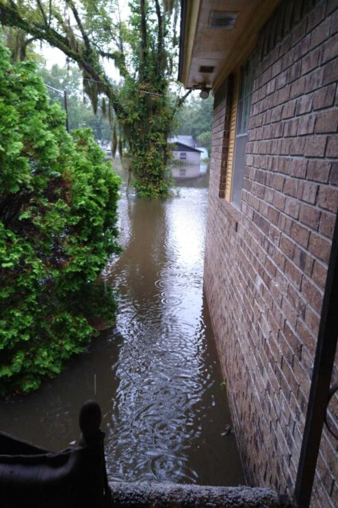 Floodwater reaches several feet above ground outside of a home.