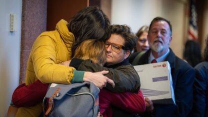 A group of people hug each other.