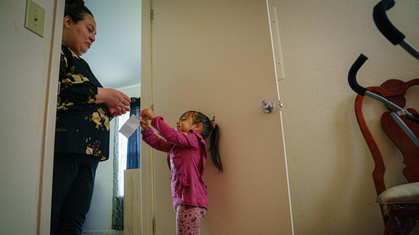 Annalinda Martinez stands with her daughter in the doorway of her bedroom.