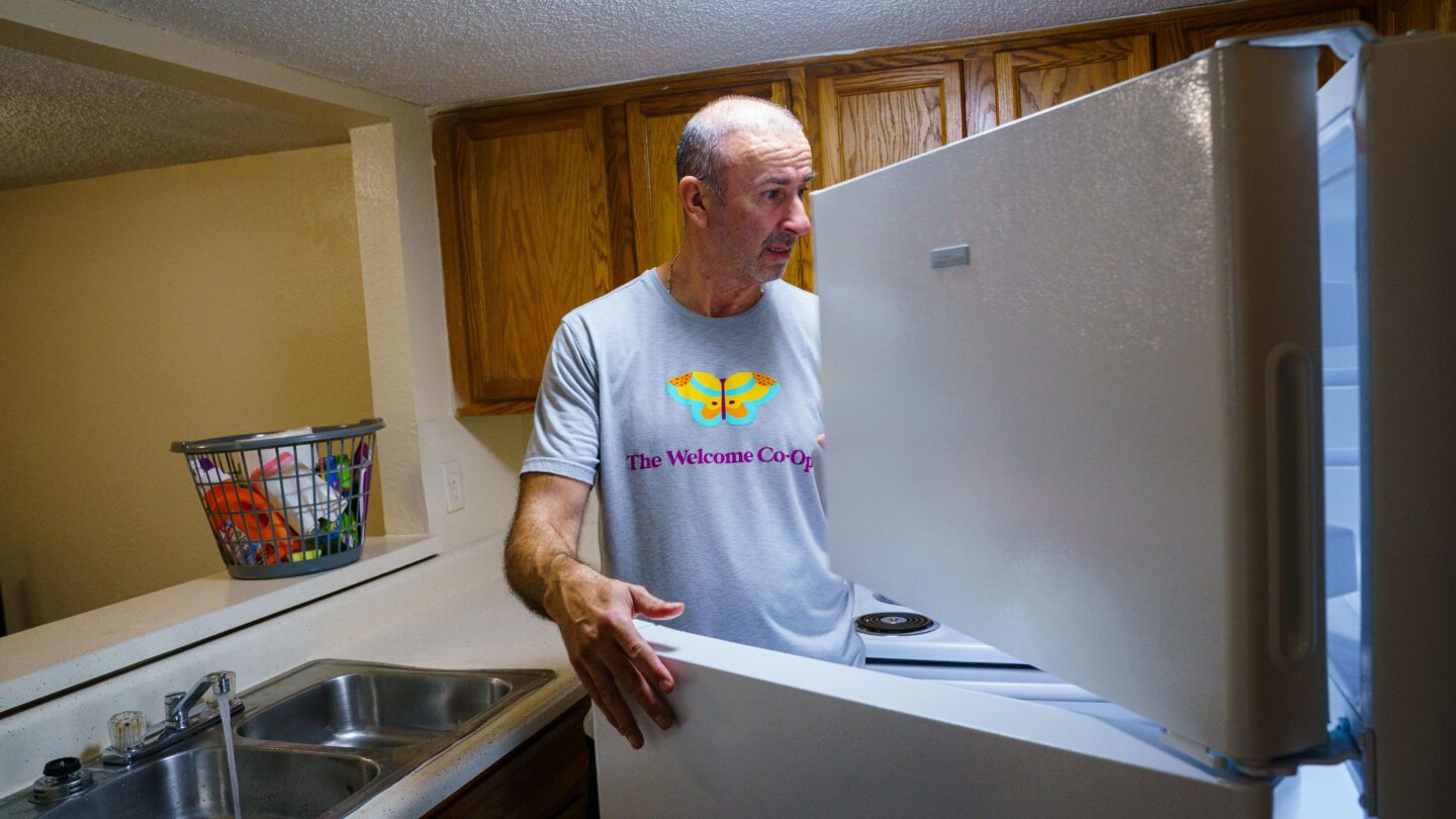 A man looks through an open fridge.