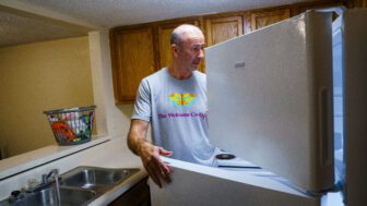 A man looks through an open fridge.