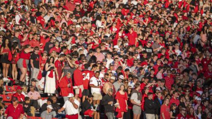 A crowd of University of Georgia fans wearing red at a football game.