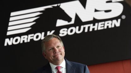 Norfolk Southern Railroad CEO Alan Shaw speaks during an interview in front of the company logo.