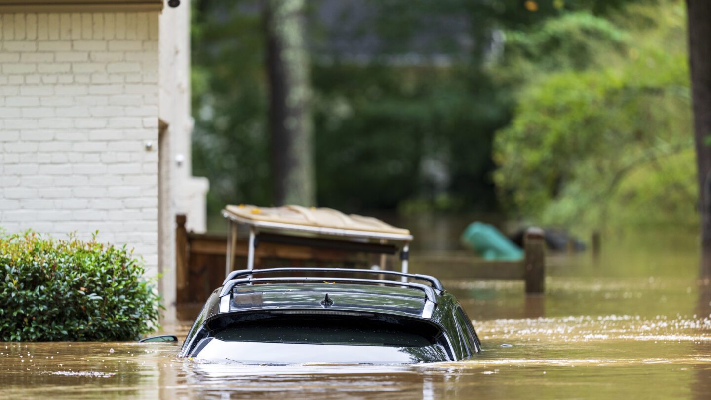 A car is nearly completely submerged outside a home.