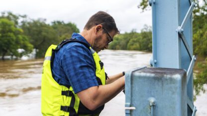 A man wearing a neon vest checks the water gauge above the Chattahoochee River.