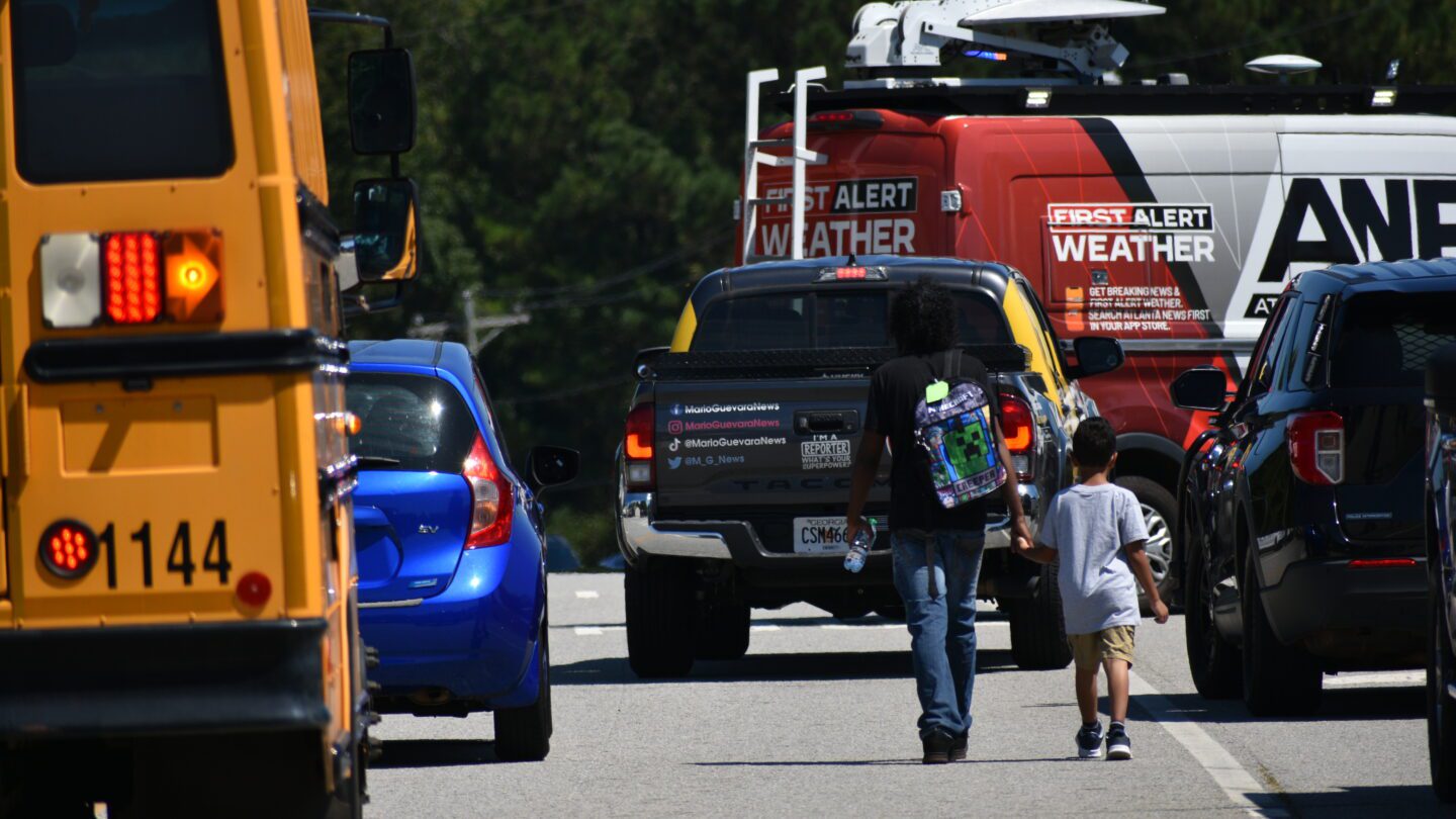 A parent and a child walk near Apalachee High School after a deadly shooting on Sept. 4, 2024.