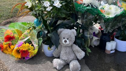 Bouquets of flowers and a teddy bear are among the items left at a flag pole near the Apalachee High School by mourners following a deadly shooting at the school on Sept. 4, 2024.