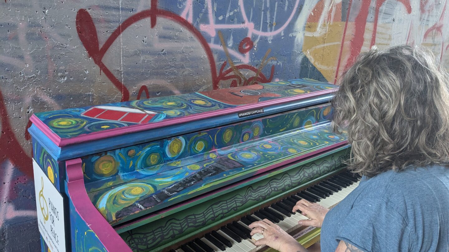 A passerby plays a colorful painted piano.