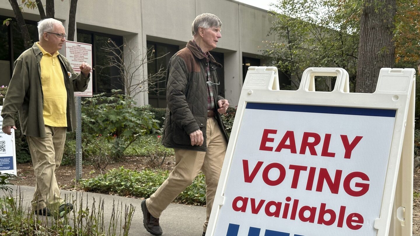 People leave after voting in the Atlanta suburb of Sandy Springs. A sign saying Early Voting available Here stands in the foreground.