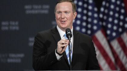 Brian Jack speaks into a microphone at a campaign event.