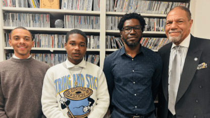 Michael Brent IV, Khalil Jackson, Larry Lowe and Michael Murphy stand in front of a bookcase.