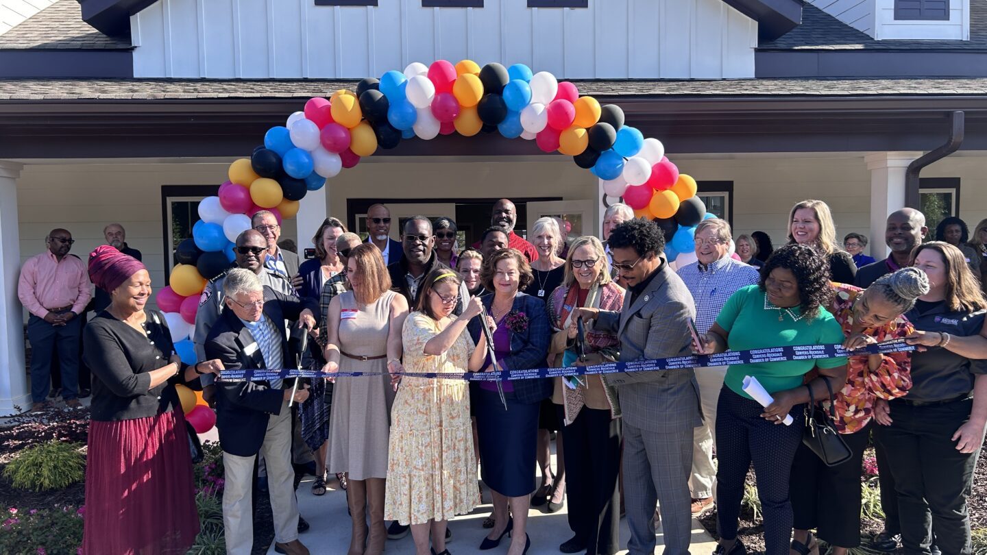 A group of people cut a ribbon in front of the community center.