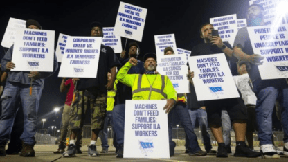 Striking dock workers hold up signs on the picket.