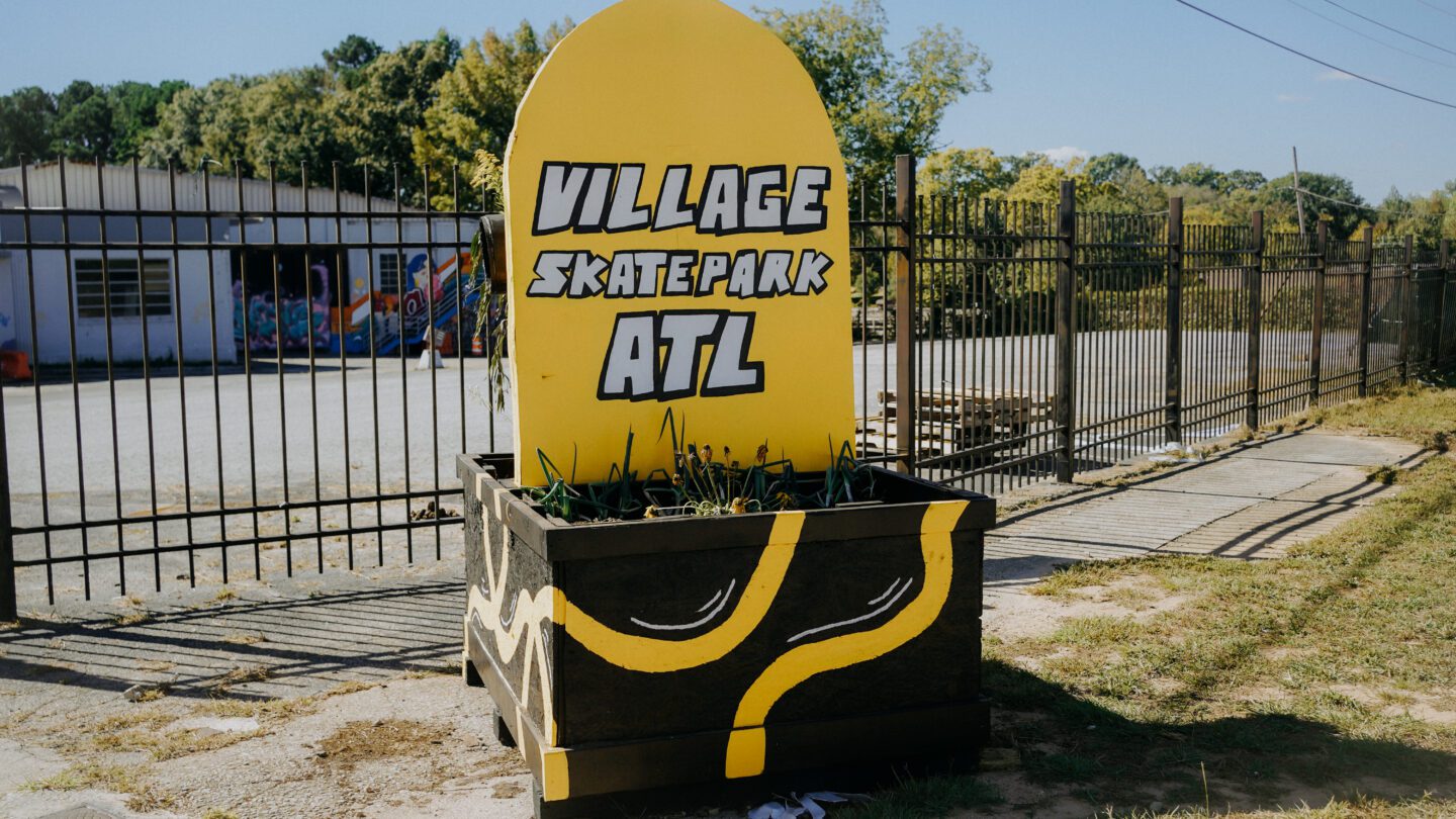 Village Skatepark ATL's new yellow sign in the shape of half of a skateboard.