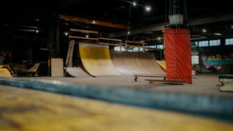 The inside of an indoor skatepark with yellow ramps and dim lighting.