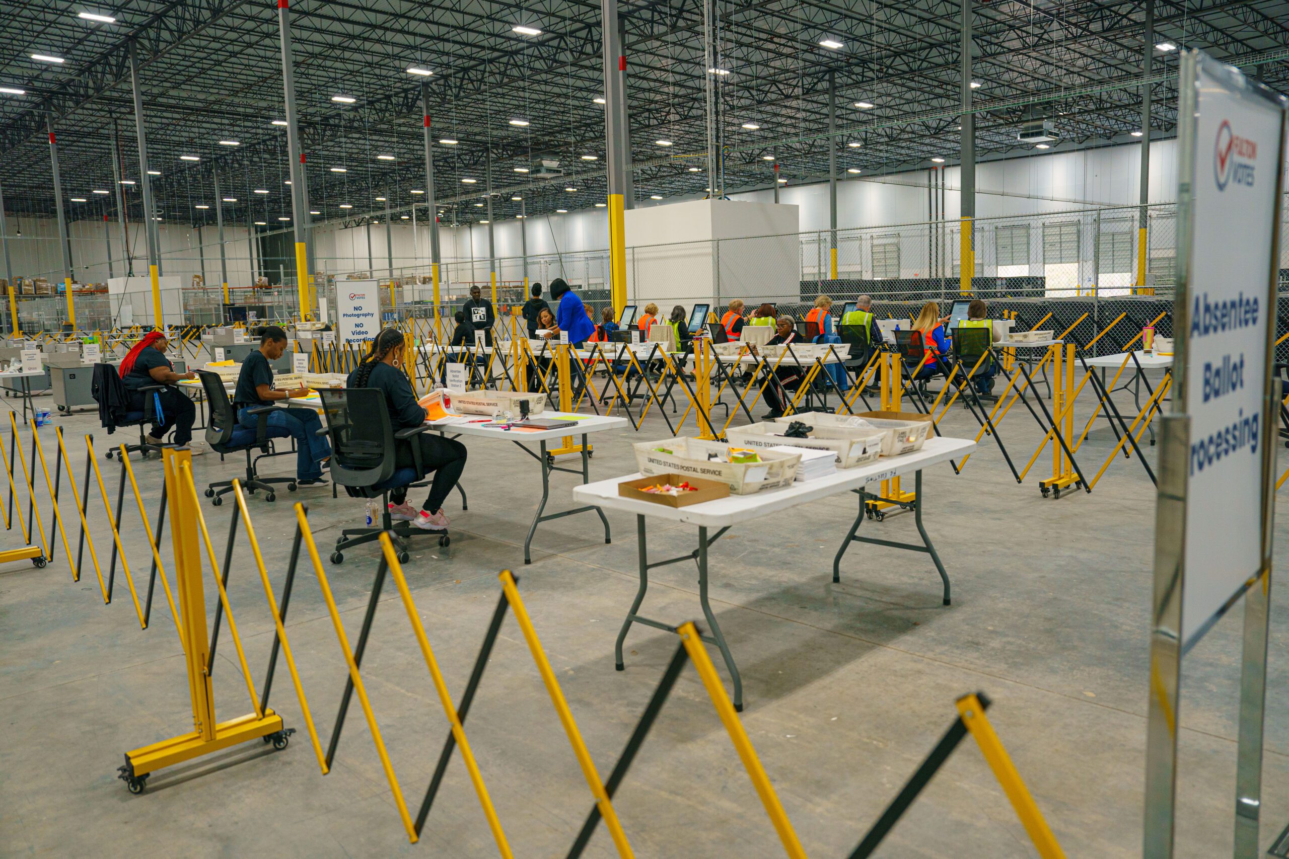 Election workers sit at a row of tables at the Fulton County Elections Hub.