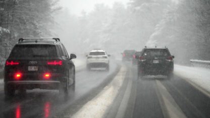 Cars drive through a snowstorm.