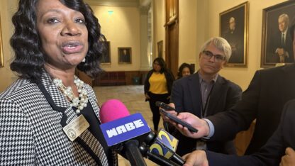 Georgia State House Minority Leader Carolyn Hugley talks to a crowd of reporters holding microphones